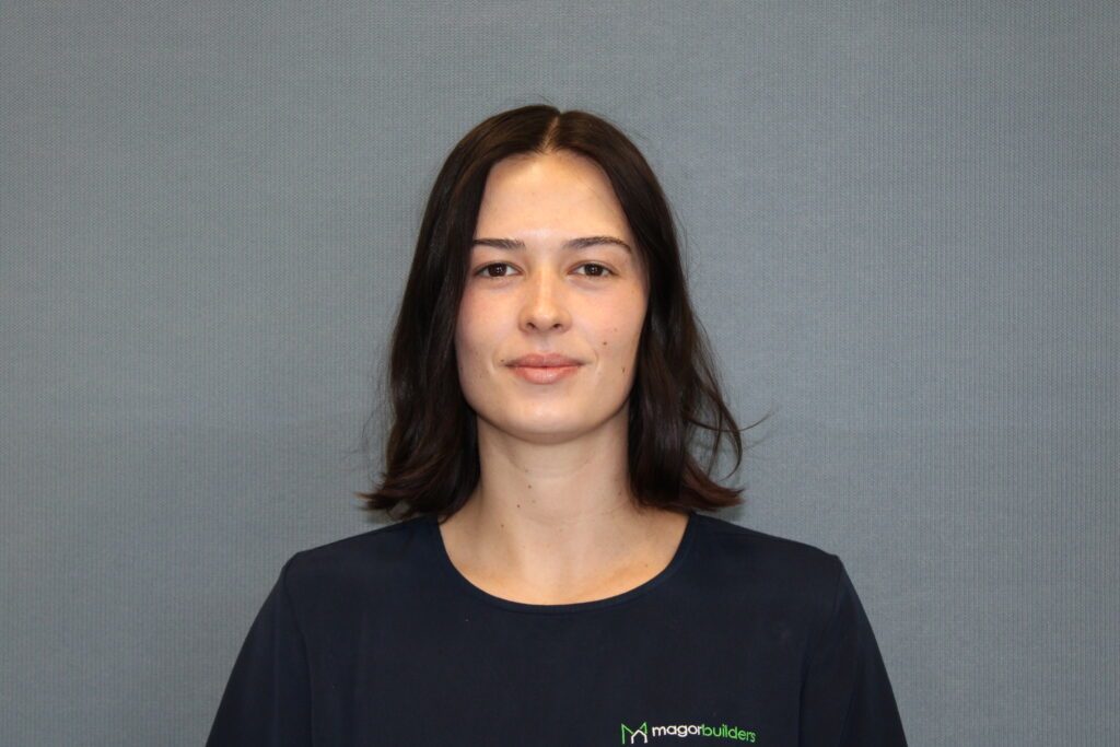 Portrait of Roxy of Magor Builders, smiling in a navy Magor Builders shirt.